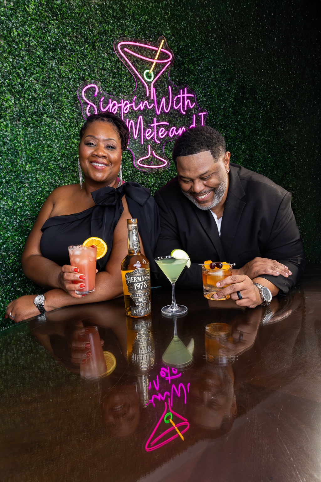 Mete and I sharing cocktails beneath their Sippin With Mete and I sign